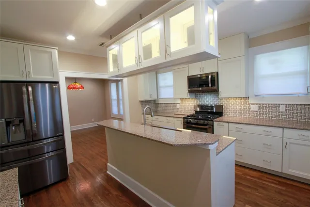 a kitchen with granite countertop a refrigerator and a stove top oven