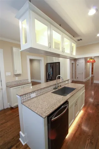 a kitchen with granite countertop a sink and a wooden floor