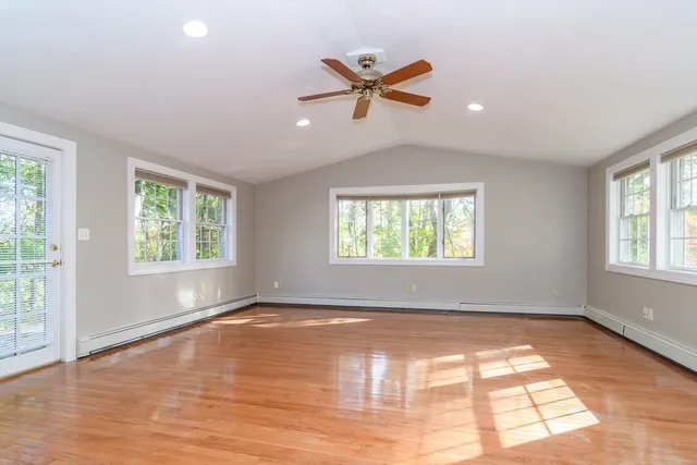an empty room with wooden floor fan and windows