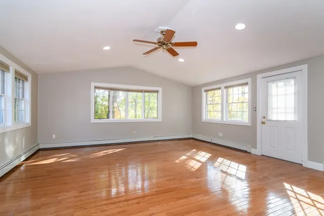 a view of empty room with wooden floor and fan