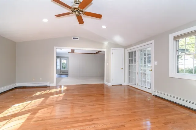 a view of an empty room with window and wooden floor