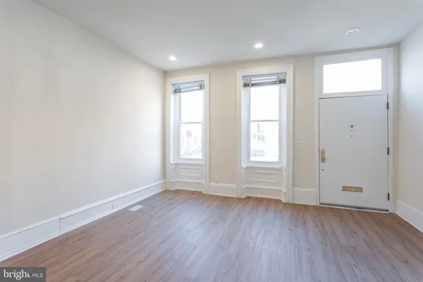 a view of a hallway with wooden floor and a bathroom