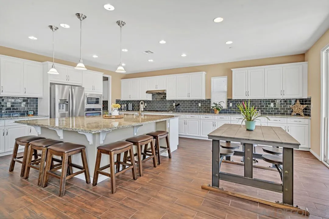 10057 Ranchitos Place Lakeside, CA 92040 - Photo 5 of 45 a kitchen with stainless steel appliances granite countertop a kitchen island a stove a table and chairs in it