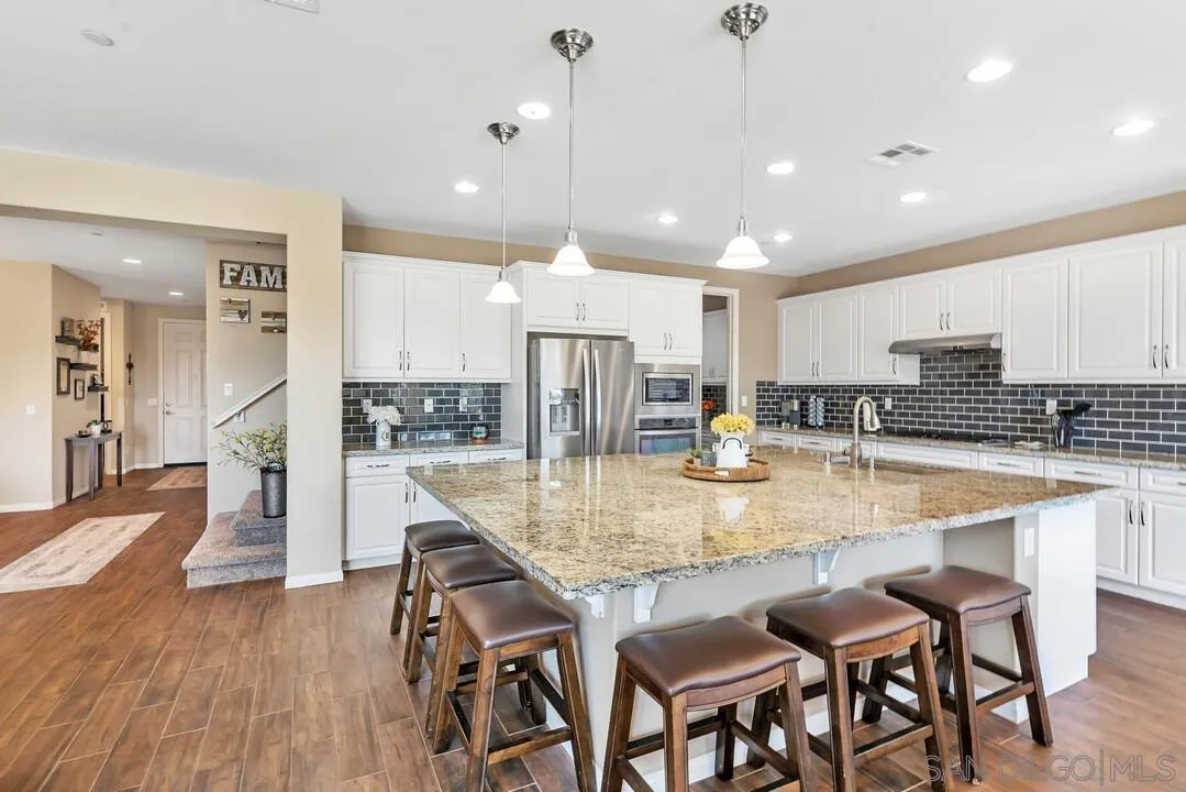 10057 Ranchitos Place Lakeside, CA 92040 - Photo 6 of 45 a kitchen with kitchen island granite countertop wooden floor cabinets and refrigerator