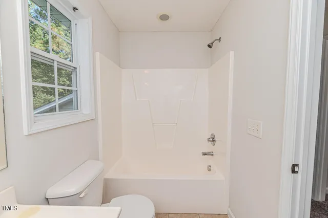 a view of an empty room with window chandelier fan