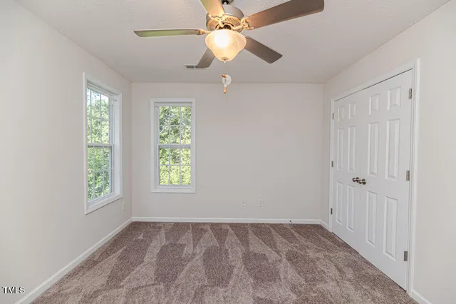 an empty room with windows and fan