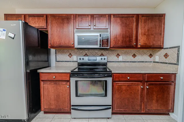 a kitchen with stainless steel appliances granite countertop a refrigerator a stove a sink and a microwave