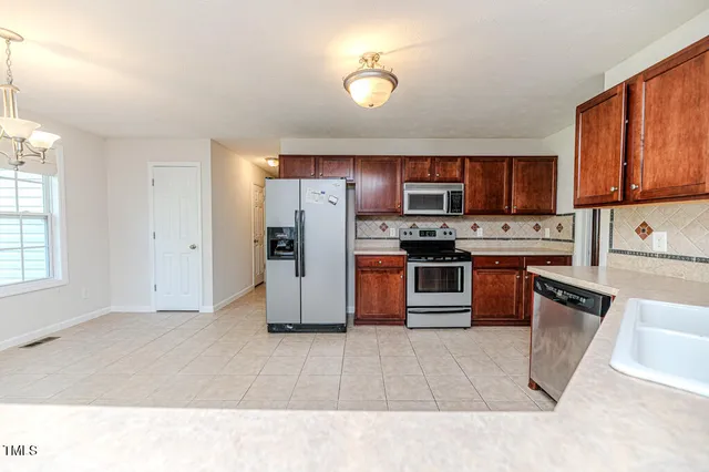 a view of an empty room with wooden floor fireplace and a window