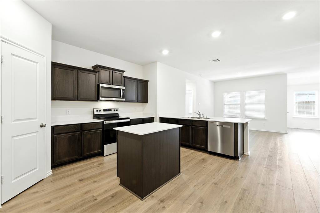 2808 Jasmine Drive Sherman, TX 75092 - Photo 13 of 38 a kitchen with stainless steel appliances kitchen island granite countertop a stove a sink a refrigerator a microwave oven with wooden cabinets and wooden floor