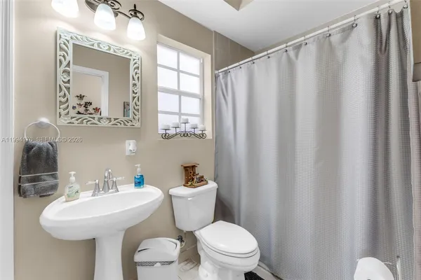 a bathroom with a sink a mirror a toilet and a window