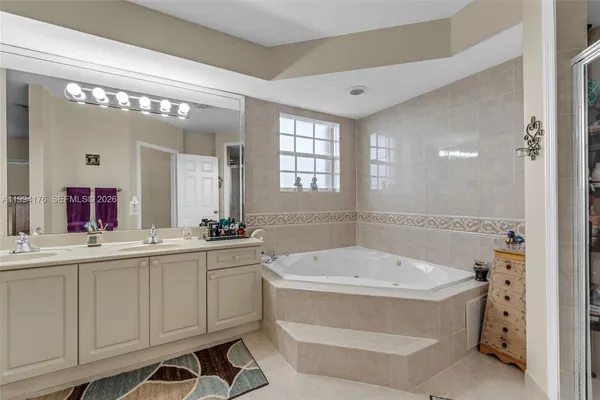 a bathroom with a bathtub a double vanity sink and mirror