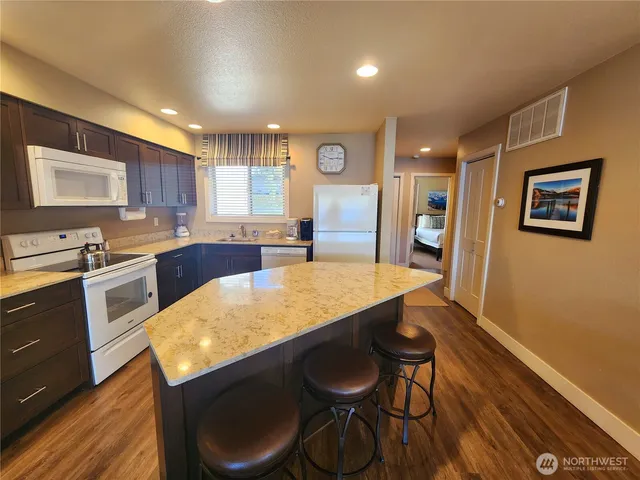 a kitchen with stainless steel appliances granite countertop a table chairs sink and cabinets
