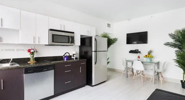 a kitchen with kitchen island granite countertop a refrigerator stove a sink dishwasher and microwave with wooden floor