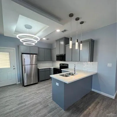 a kitchen with kitchen island a counter top space a sink stainless steel appliances and cabinets