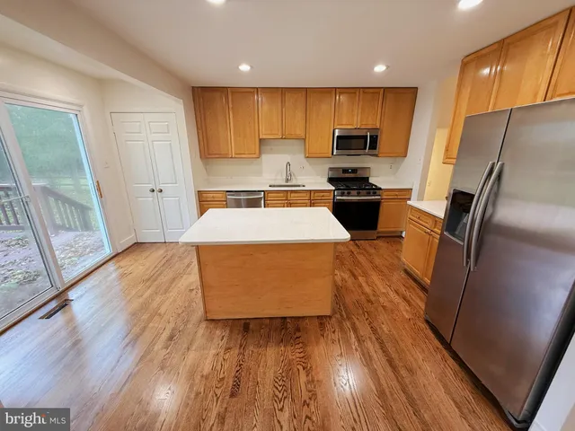 a kitchen with stainless steel appliances a refrigerator a sink a stove a microwave and wooden floor