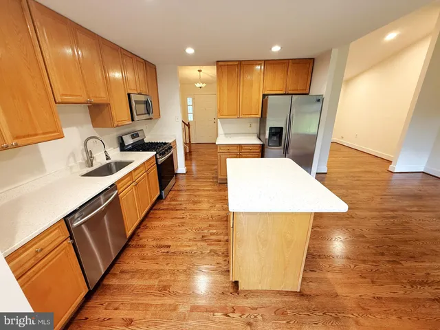 a large kitchen with stainless steel appliances kitchen island granite countertop a large counter top a refrigerator and cabinets