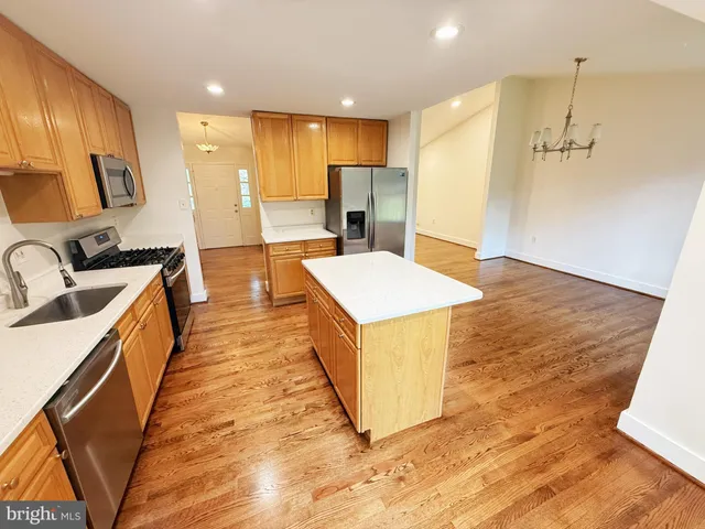 a large kitchen with stainless steel appliances a large counter top a sink a refrigerator and a stove