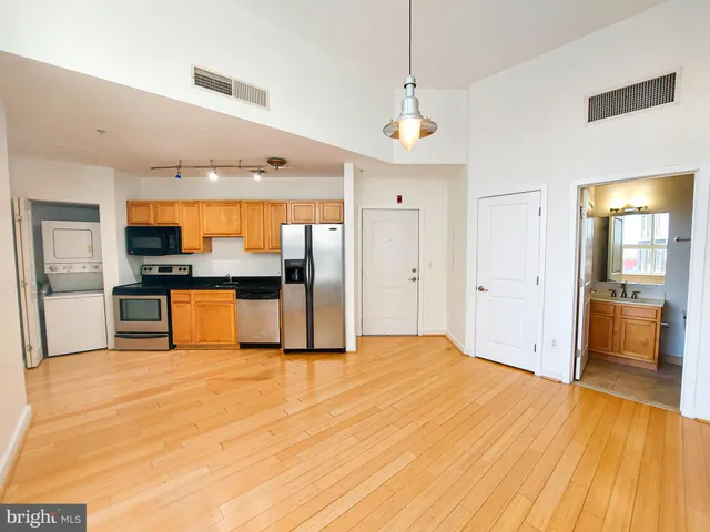 a view of kitchen with stainless steel appliances kitchen island wooden floor and refrigerator