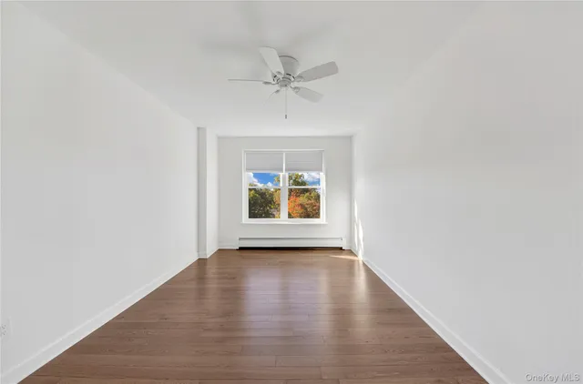 a view of an empty room with a window and wooden floor