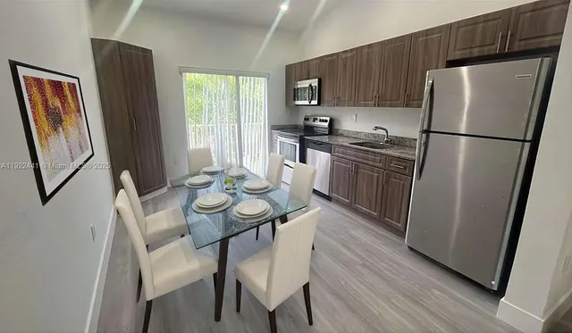 a kitchen with stainless steel appliances granite countertop a refrigerator a stove a sink a dining table and chairs