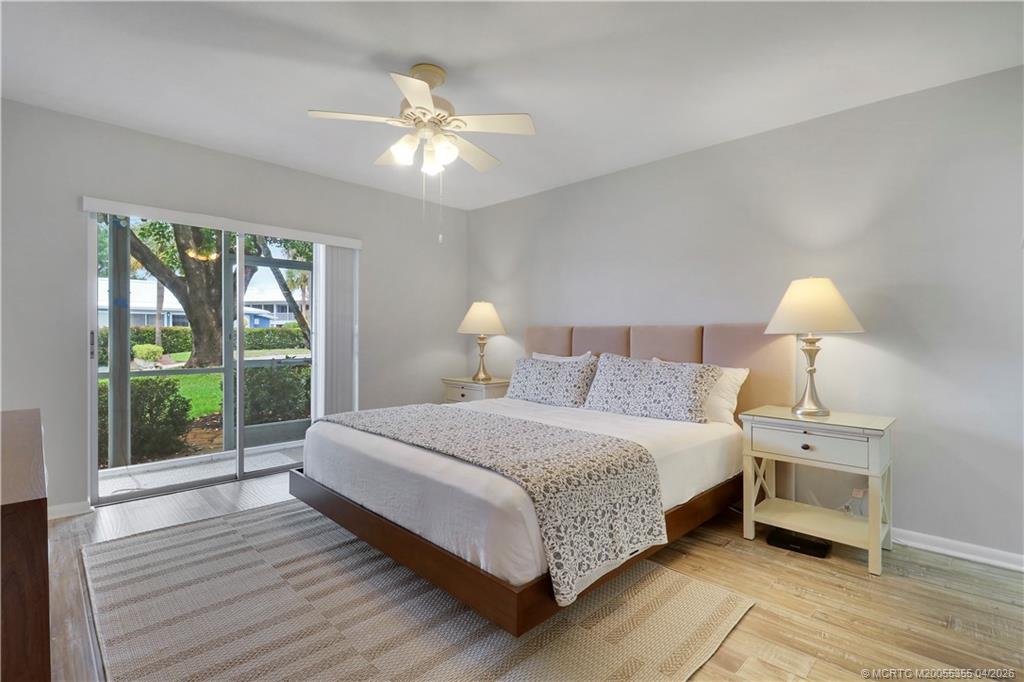1862 Southwest Palm City Road, Unit 103 Stuart, FL 34994 - Photo 14 of 29 Spacious primary bedroom with direct access to the screened patio, offering natural light and a peaceful connection to the outdoors. Features wood-look tile flooring and a clean, neutral palette.