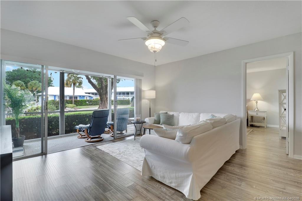 1862 Southwest Palm City Road, Unit 103 Stuart, FL 34994 - Photo 5 of 29 Spacious, light-filled living area with a wall of sliding glass doors opening to a screened patio. Enjoy seamless indoor-outdoor living with peaceful green and canal views, perfect for relaxing or entertaining.