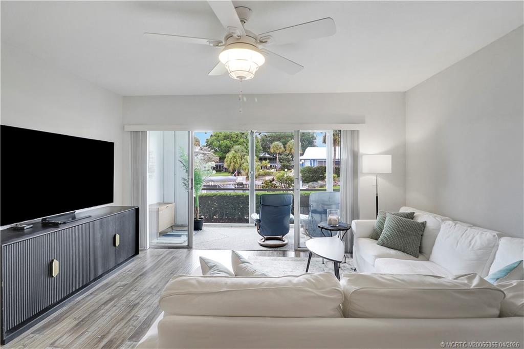 1862 Southwest Palm City Road, Unit 103 Stuart, FL 34994 - Photo 6 of 29 Spacious, light-filled living area with a wall of sliding glass doors opening to a screened patio. Enjoy seamless indoor-outdoor living with peaceful green and canal views, perfect for relaxing or entertaining.