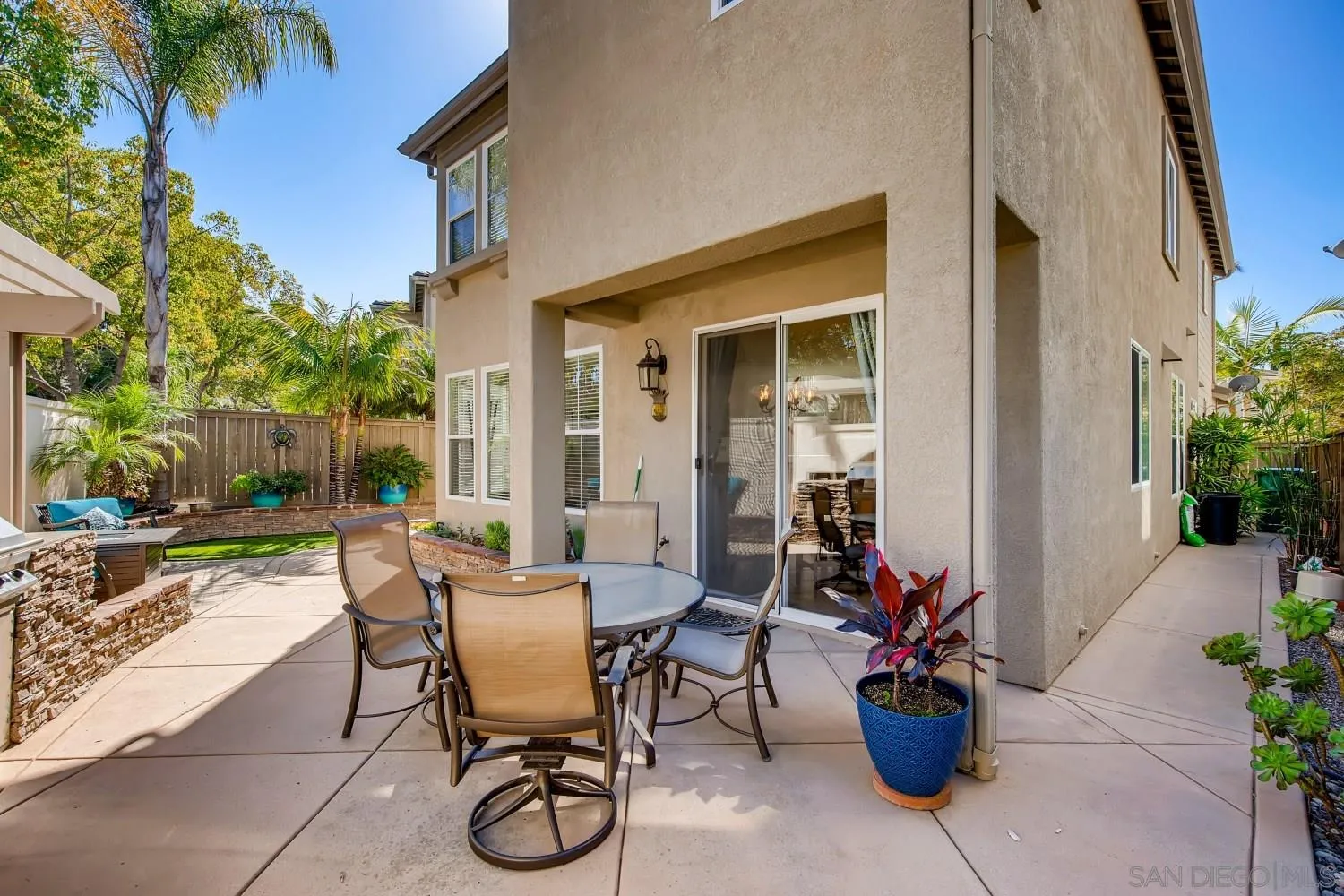 1332 Enchante Way Oceanside, CA 92056 - Photo 25 of 28 a view of a patio with table and chairs potted plants and palm trees