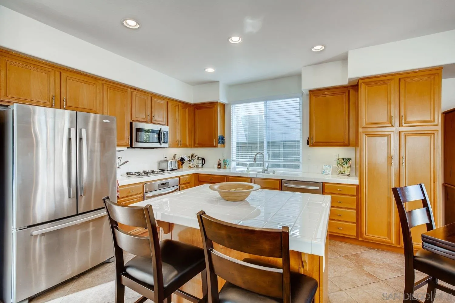 1332 Enchante Way Oceanside, CA 92056 - Photo 7 of 28 a kitchen with stainless steel appliances granite countertop a refrigerator a stove a sink a dining table and chairs with wooden floor