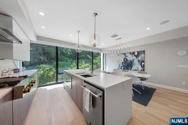 a kitchen with stainless steel appliances a stove a sink a refrigerator a center island and couches