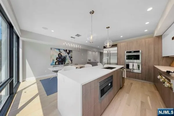 a large kitchen with kitchen island a stove a sink a refrigerator and a refrigerator with wooden floor