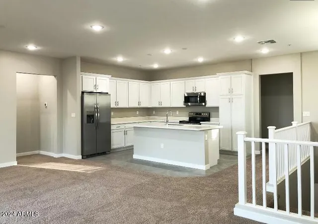 a kitchen with granite countertop a refrigerator and white cabinets