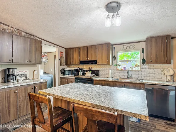 a kitchen with kitchen island granite countertop a center island a stove cabinets a sink and a counter space