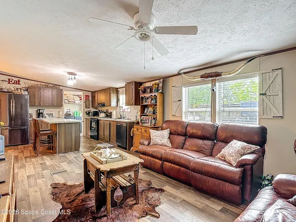 a living room with furniture kitchen view and large windows