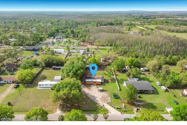 an aerial view of residential houses with outdoor space and trees