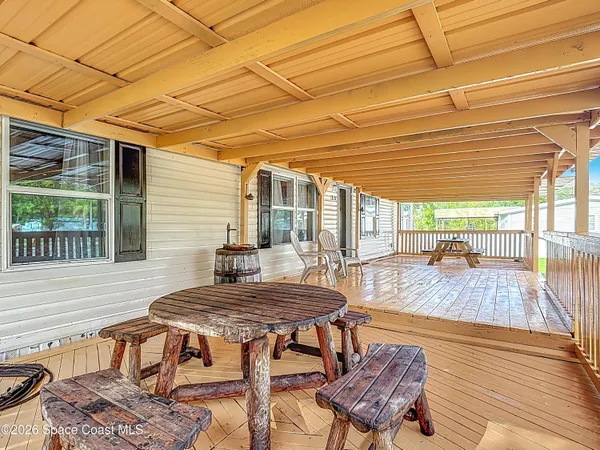 a view of a patio with table and chairs with wooden floor and fence