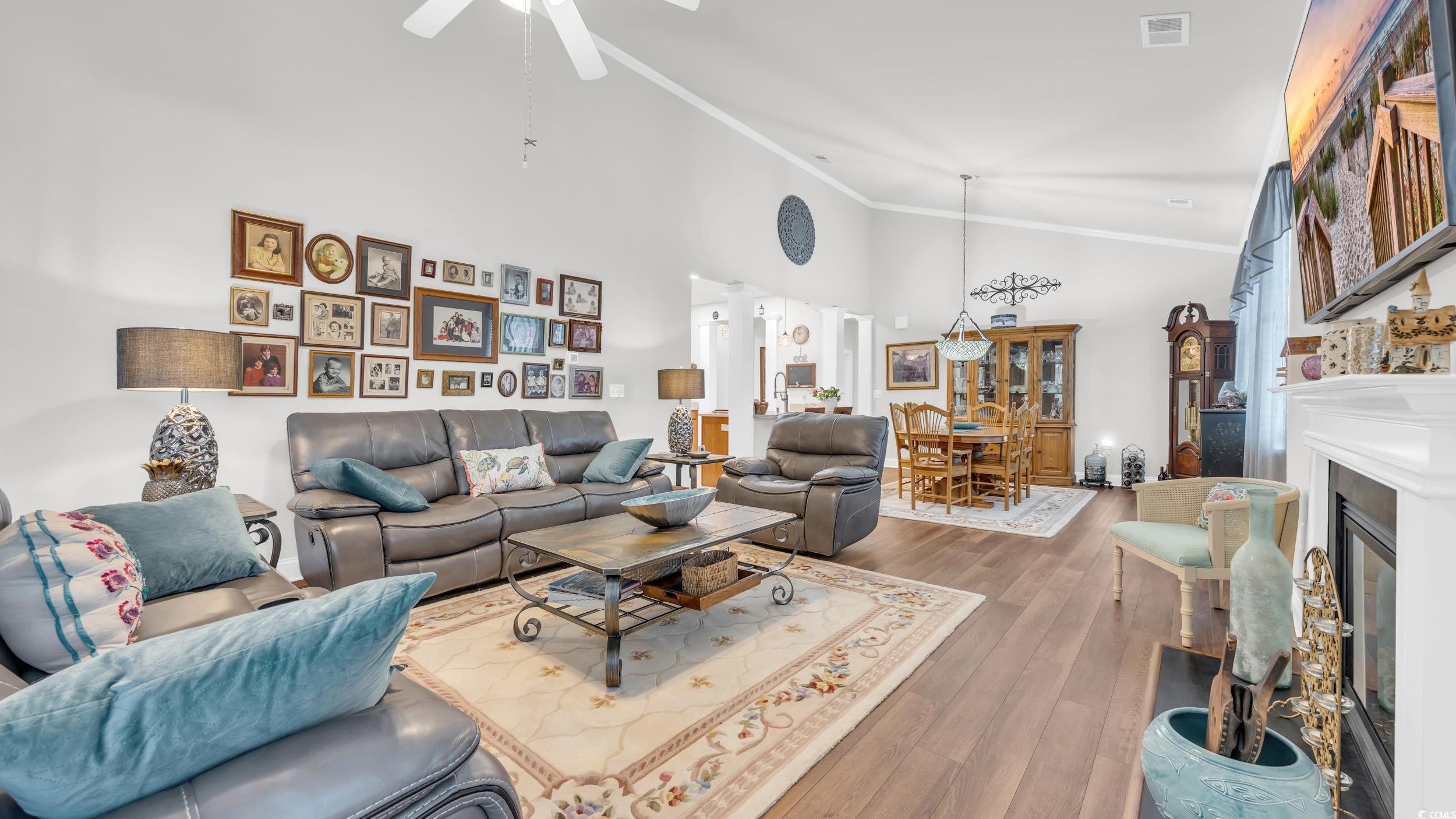 730 Pickering Drive, Unit 301 Murrells Inlet, SC 29576 - Photo 10 of 30 Living room featuring crown molding, a glass covered fireplace, dark wood-style flooring, high vaulted ceiling, and ceiling fan
