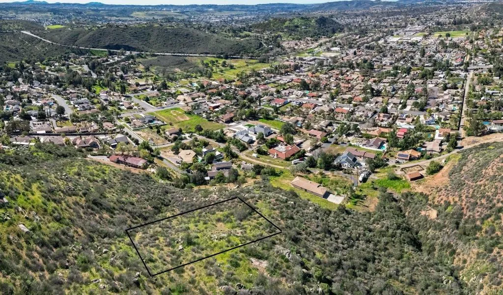an aerial view of residential houses with outdoor space and trees