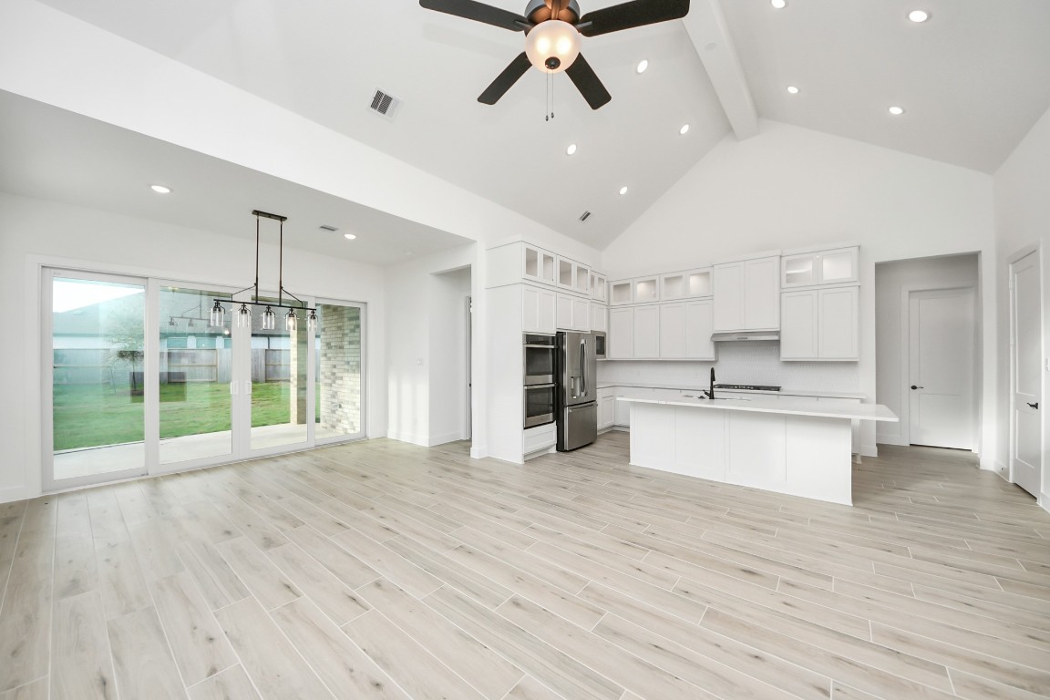 a view of an empty room with kitchen appliances and furniture