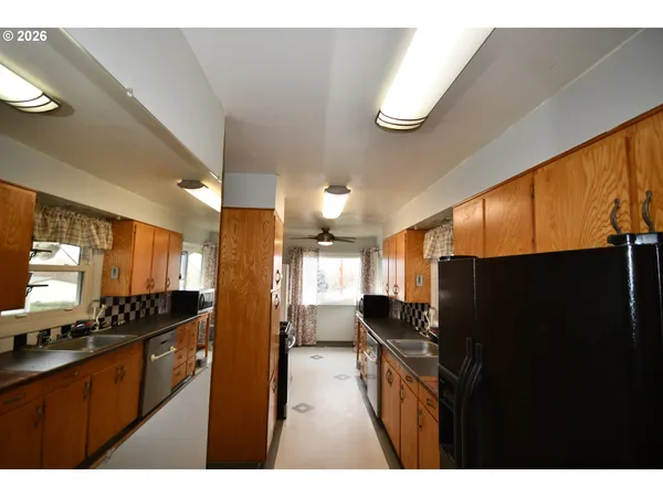 a kitchen view with stainless steel appliances kitchen island granite countertop a refrigerator a stove and a sink
