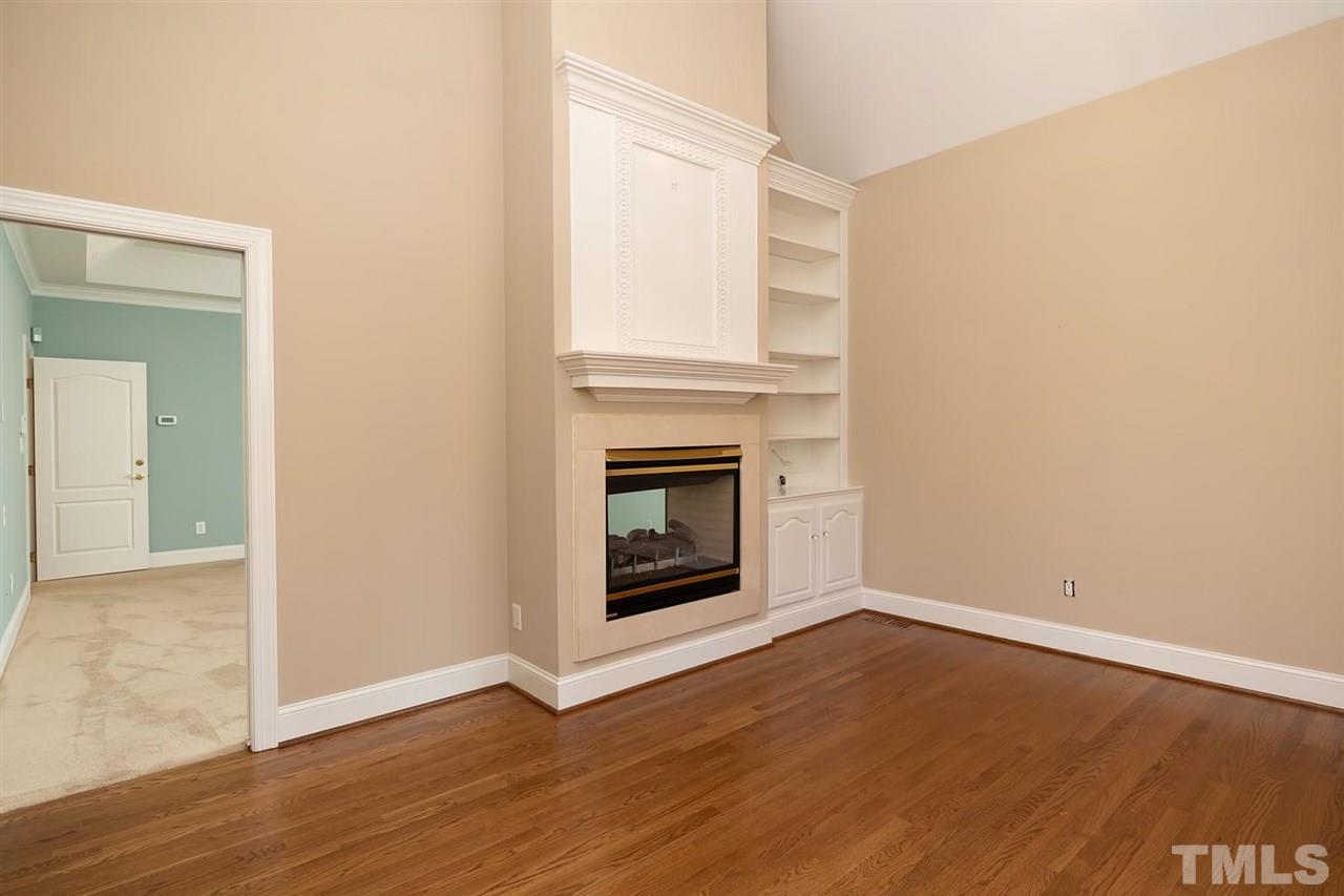 5220 Deergrass Court Raleigh, NC 27613 - Photo 14 of 25 an empty room with wooden floor a fireplace and windows