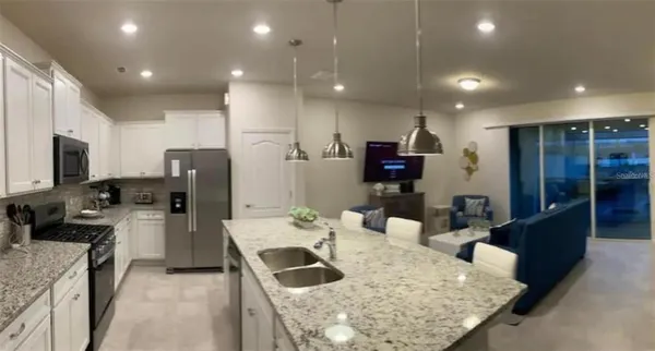 a kitchen with stainless steel appliances kitchen island granite countertop a refrigerator and a sink