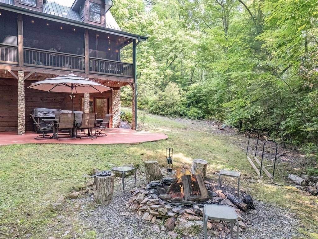 781 Mangum's Trail Blue Ridge, GA 30513 - Photo 61 of 65 a view of a patio with table and chairs under an umbrella with large trees