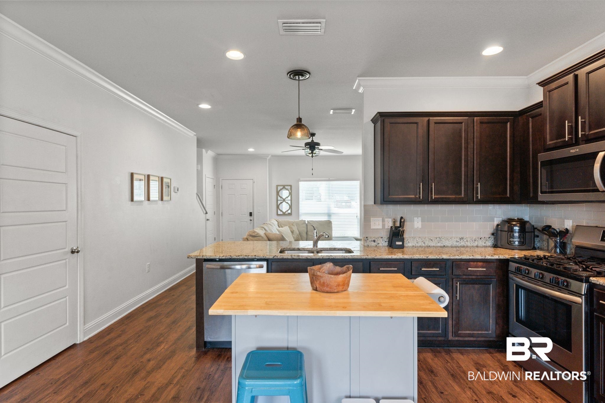 12711 Chickadee Lane Daphne, AL 36527 - Photo 11 of 39 Kitchen with ornamental molding, appliances with stainless steel finishes, dark brown cabinetry, backsplash, and a peninsula