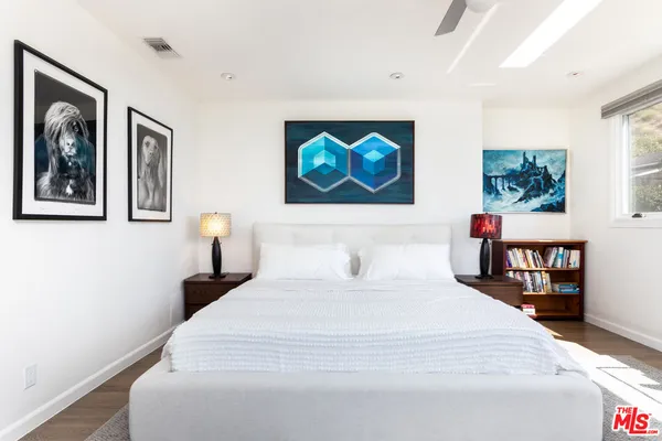 a bedroom with bed and paintings on the wall