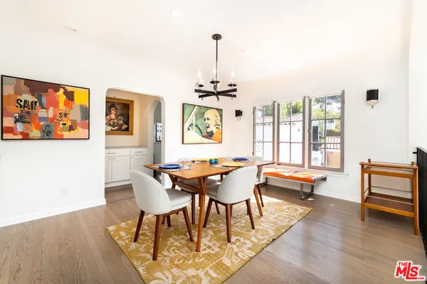 a dining room with wooden floor a chandelier a glass table and chairs