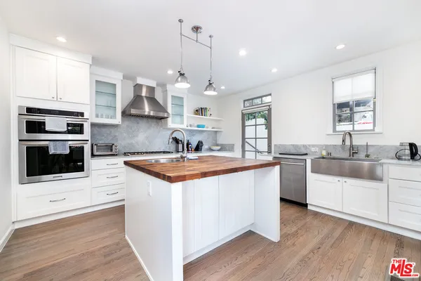 a kitchen with stainless steel appliances a sink a stove a microwave a center island and cabinets