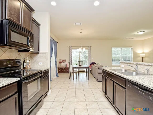 a kitchen with stainless steel appliances granite countertop a stove a sink and a microwave