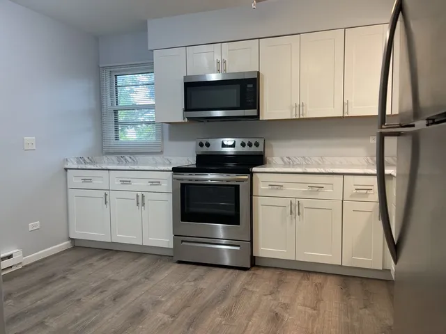 a kitchen with stainless steel appliances a stove a microwave and white cabinets