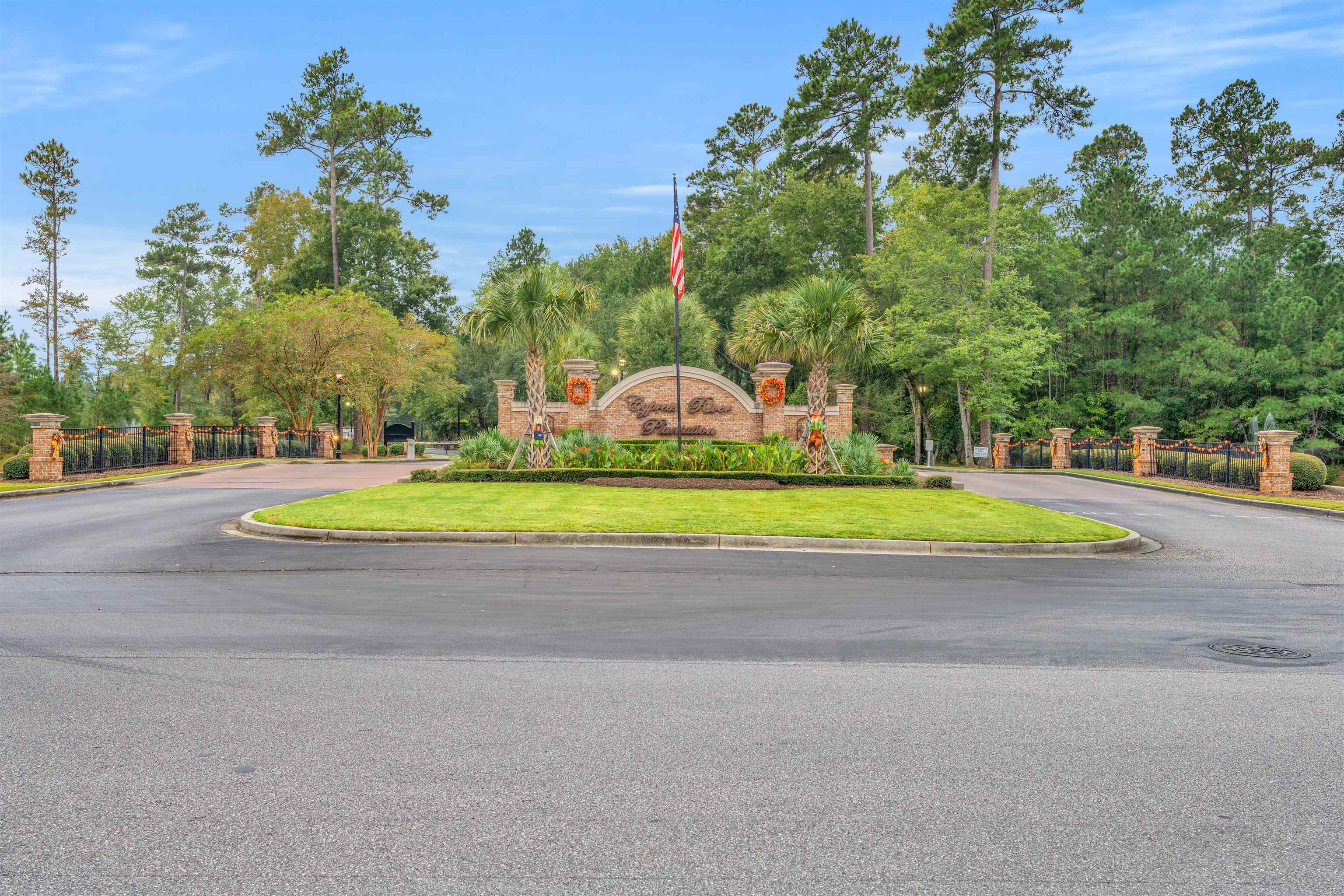 411 Chamberlin Road Myrtle Beach, SC 29588 - Photo 40 of 40 Community / neighborhood sign with view of wooded area and curved driveway